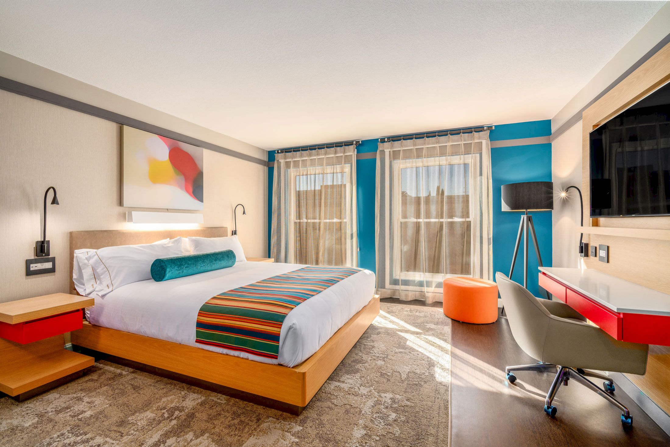 A hotel room with a bed, desk, chair, and TV